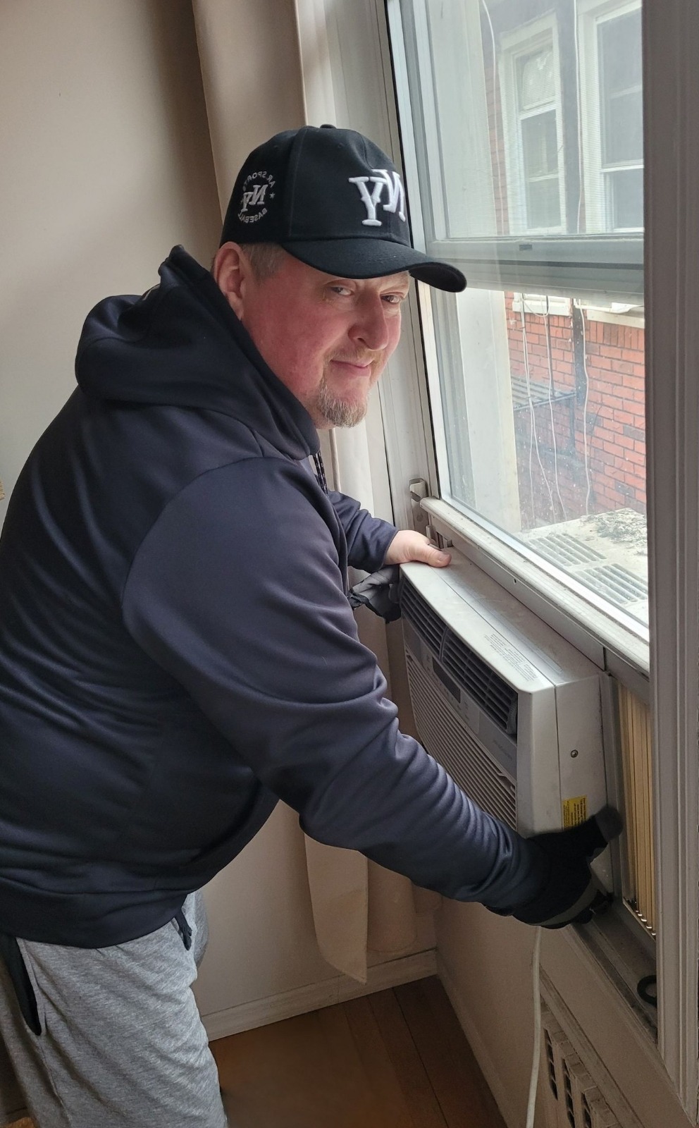 technician installing window AC unit in NYC apartment
