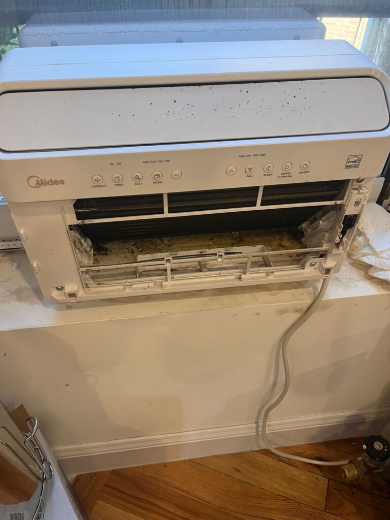 Window air conditioner opened for cleaning with visible dust and dirt inside unit in New York apartment