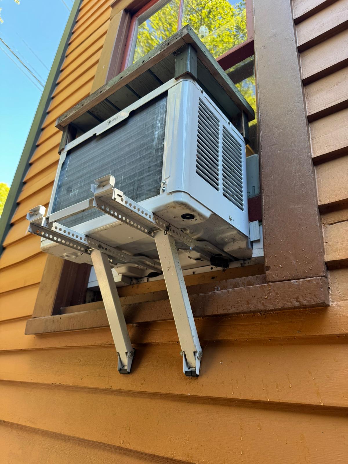 Midea window AC installation with proper drainage and support bracket in NYC