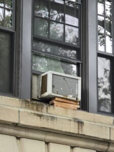 Improper window air conditioner installation in NYC apartment with no support bracket causing safety risk